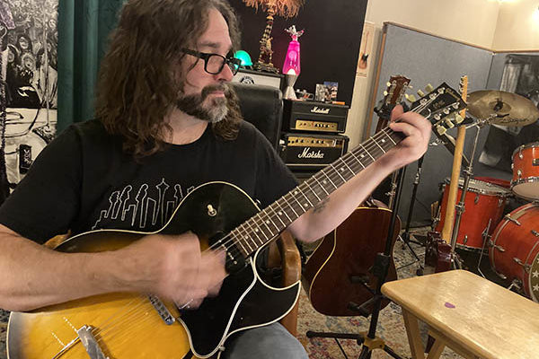 David Hillman strumming guitar during guitar lessons in studio
